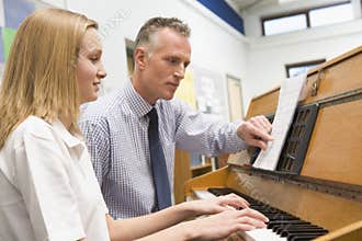 Teacher with schoolgirl playing piano