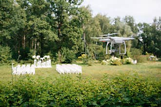 Videography wedding ceremony from the air a small spy quad copter scout drone flying through the trees in forest.