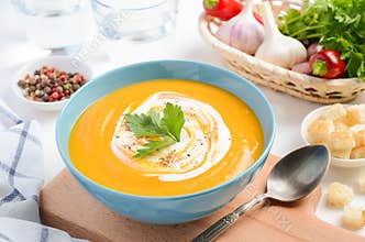 Pumpkin soup with cream and parsley on white background