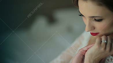 Beautiful pensive bride softly touches her face and dreamily closes her eyes