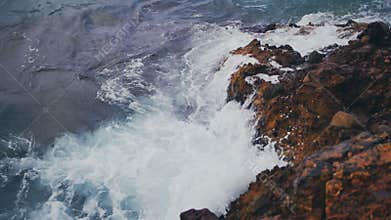 Sea waves crash against the rock in slow motion