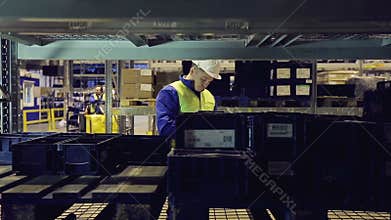 Warehouse worker going along shelves and writing