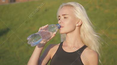 Sporty woman drinking water outdoor on sunny day on sunset