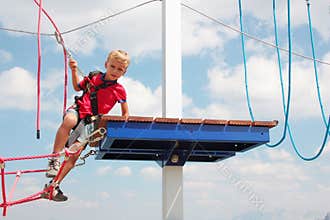 Blond hair kid playing rope course outdoor