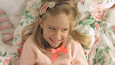 Adorable little girl lying on the bed and laughing gaily