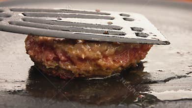 Burger flipped on the grill with kitchen spatula