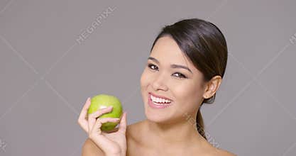 Laughing healthy young woman with a green apple