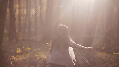 Frightened little girl running in the dense forest and suddenly stops in the bright sunshine. Scary story, danger