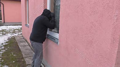 Robber with crowbar watching in window