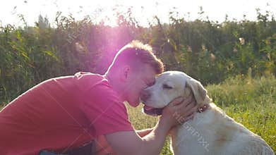 Young man caress, hugging and kissing his labrador outdoor at nature. Playing with golden retriver. Dog licking male