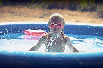 Blond little girl playing in the pool