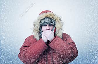 Frozen man in winter clothes warming hands, cold, snow, blizzard