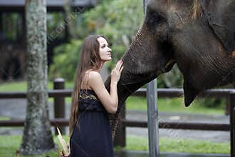 Woman with the elephant, treats, and pats him on the snout, with