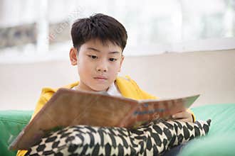 Happy asian child reading book with smile face.