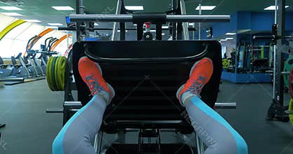 Close up shoes of a fit young woman doing leg press in the gym. Closeup of a fit young woman doing leg presses in the