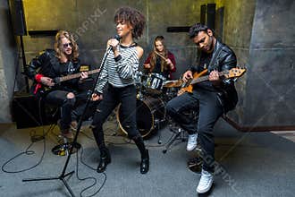 Multiethnic rock and roll band rehearsing in musical studio