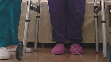Care assistant teaching elder disabled woman how to walk with walker