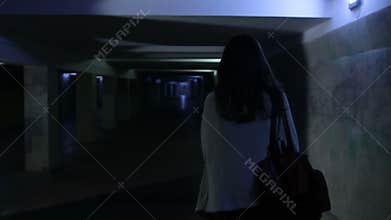 Scared woman screaming in dark underpass at night