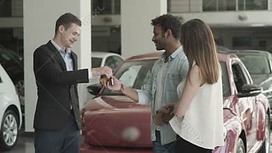 Happy couple just got a keys from a new car in car showroom