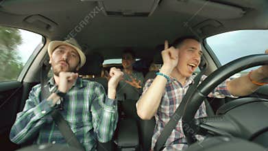 Group of happy friends in car singing and dancing while drive road trip