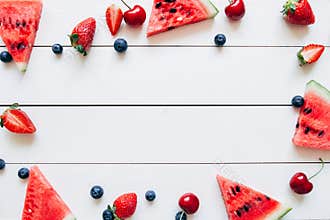 Summer fruits. Fresh juicy berries and watermelon on the white wooden table, top view