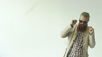 Slowmotion of young funny bearded man in sunglasses dancing on white background