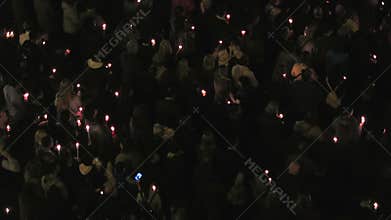 Gathered crowd holding candles at night.