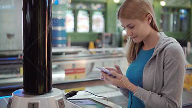 Beautiful attractive woman in airport terminal. Standing near charging stand pluging in smartphone
