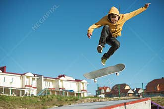 A teenager skateboarder does an flip trick in a skatepark on the outskirts of the city