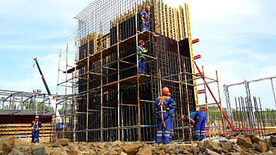 Working people erect reinforced mesh under the foundation at the construction site