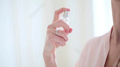 The girl applies perfume to her neck