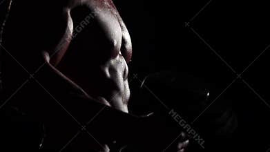Athlete lifts a bar to train for competitions. Black background. Slow motion. Close up. Silhouette