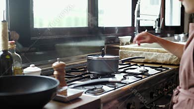 Female chef checks on boiling water in pot