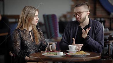 Loving couple having date in cafeteria. Happy man and woman sitting at the served table with food and beverages spending