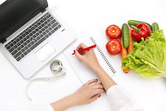 Vegetable diet nutrition or medicaments concept. Doctors hands writing diet plan, ripe vegetable composition, laptop and measuring