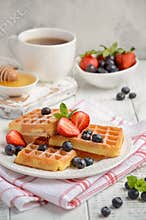 Waffles with fresh berries on wooden background