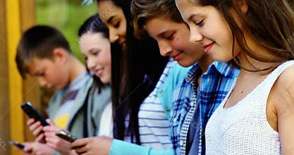 Group of school friends using mobile phone outside school