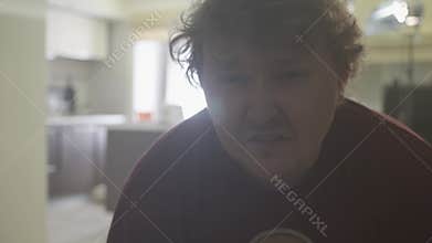 Fat curly hair caucasian sad man crying in bright living room