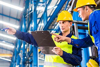 Worker and forklift driver in industrial factory