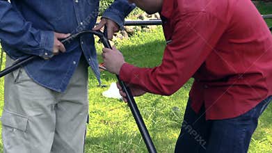 Zoom in of two men construct garden arbor roof frame