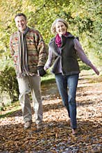 Senior couple walking through autumn woods