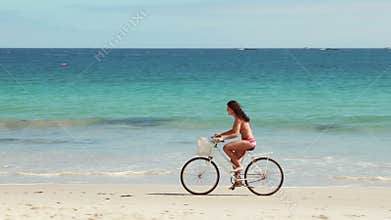 Carefree woman going on a bike ride on the beach