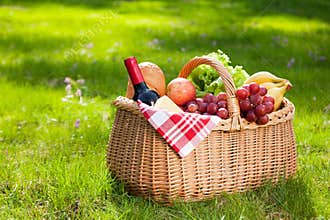 Picnic basket with food on green grass.