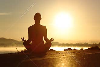 Silhouette of a fitness woman exercising yoga meditation exercises