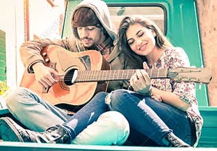 Romantic couple of lovers playing guitar on vintage minicar