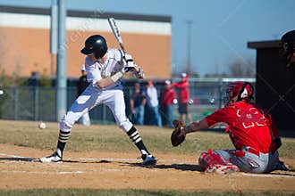 High school baseball batter takes a pitch at the knees