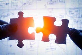 Hands trying to fit two puzzle pieces together