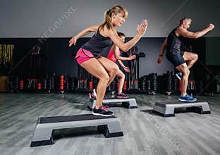 Woman trainer doing aerobic class with steppers in