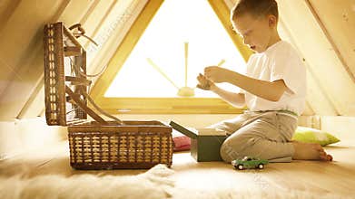 Little blond boy playing with his toys in the attic
