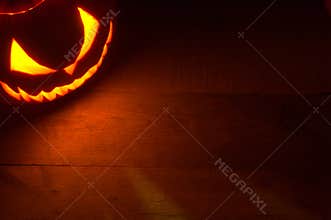Spooky halloween background with evil face of jack o lantern in the corner